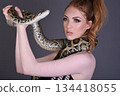 Beautiful redhead girl posing with her pet snake in the studio 134418055
