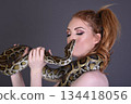 Beautiful redhead girl posing with her pet snake in the studio 134418056