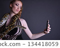 Beautiful redhead girl posing with her pet snake in the studio 134418059