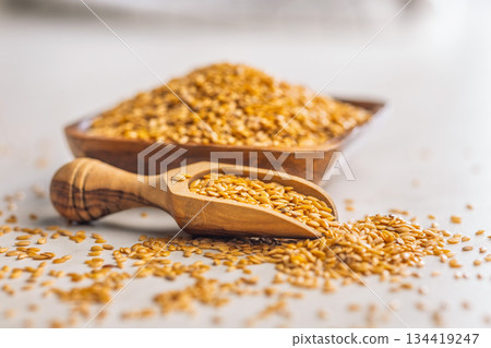 Golden linseed or flaxseed. Healthy flax seed in wooden scoop on kitchen table. 134419247