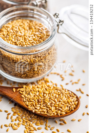 Golden linseed or flaxseed. Healthy flax seed on wooden spoon on kitchen table. 134419252