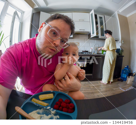 Playful moment in the kitchen with baby and parent Playful moment in the kitchen with baby and parent 134419456