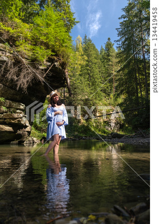 Woman Enjoying a Tranquil Forest Stream Woman Enjoying a Tranquil Forest Stream 134419458