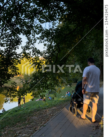 Man with Stroller by Pond in Park Man with Stroller by Pond in Park 134419475