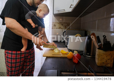 Father Multitasking: Cooking with Baby in Kitchen Father Multitasking: Cooking with Baby in Kitchen 134419478