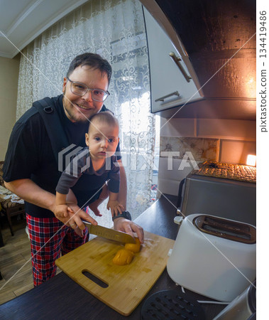 Father Cooking with Baby in Carrier Father Cooking with Baby in Carrier 134419486