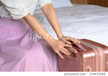 飯店房間裡，女人的手正在搬運行李箱 134419569