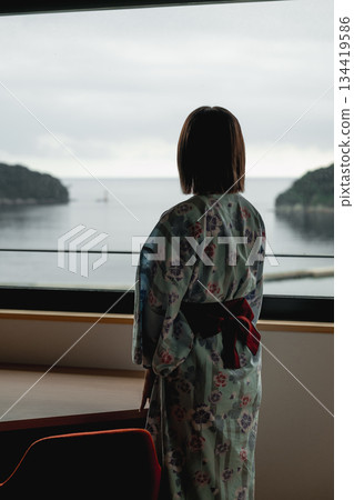A woman in a yukata looking out the window at the sea A woman in a yukata looking out the window at the sea 134419586