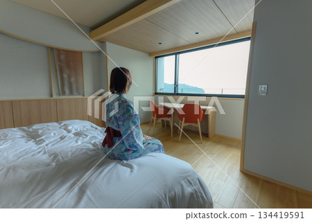 A woman in a yukata looks out the window 134419591