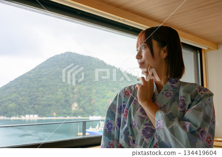 一位身穿浴衣的女子正望著窗外的自然景色。 134419604