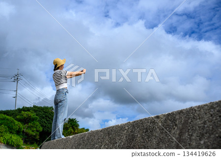 A woman taking a selfie with a cloudy sky in the background A woman taking a selfie with a cloudy sky in the background 134419626