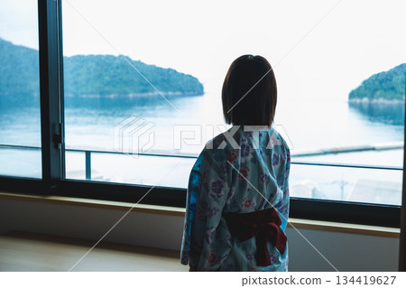 一位身穿浴衣的女子正望著窗外的大海。 134419627