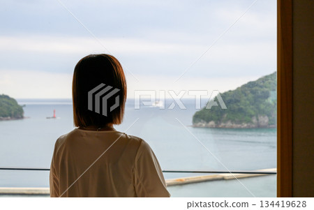一位女子背對著鏡頭，望著窗外的大海。 134419628