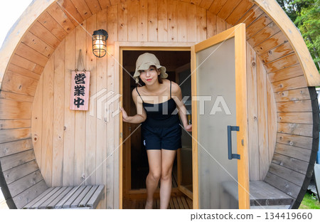 A woman coming out of the barrel sauna entrance A woman coming out of the barrel sauna entrance 134419660