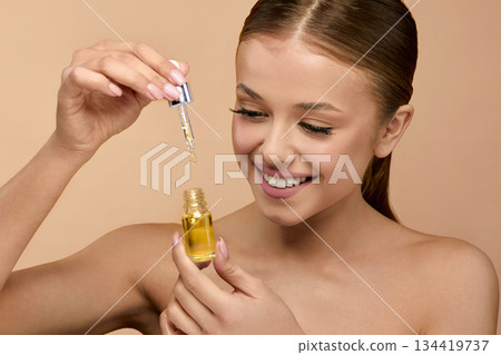 A young woman applies a serum with focus on her radiant skin, showcasing beauty techniques A young woman applies a serum with focus on her radiant skin, showcasing beauty techniques 134419737