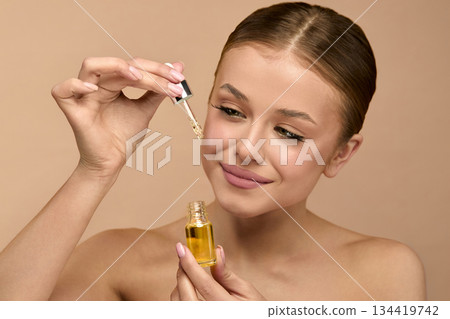 Beauty woman applying serum for skincare in studio with natural light to enhance skin glow and health Beauty woman applying serum for skincare in studio with natural light to enhance skin glow and health 134419742