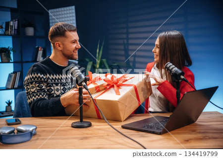 Happy, holding new year gift boxes. Radio hosts recording podcast 134419799