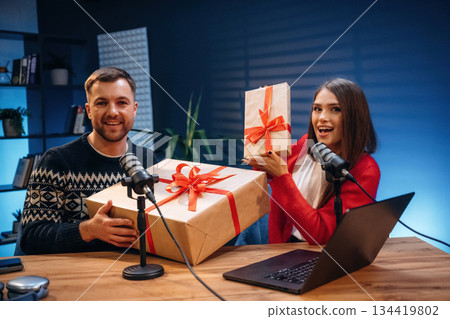 Happy, holding new year gift boxes. Radio hosts recording podcast Happy, holding new year gift boxes. Radio hosts recording podcast 134419802
