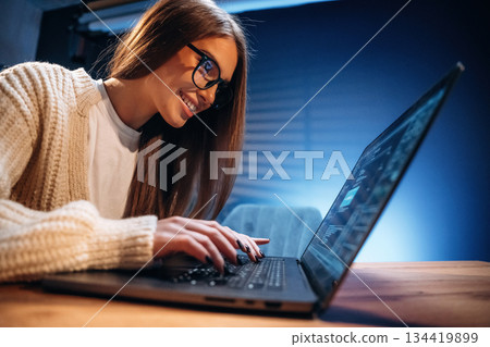 Reflection in the glasses. Female programmer, IT worker is sitting by the laptop Reflection in the glasses. Female programmer, IT worker is sitting by the laptop 134419899