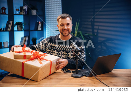 Christmas present, gift box. Man with microphone in the studio, conception of podcast 134419985