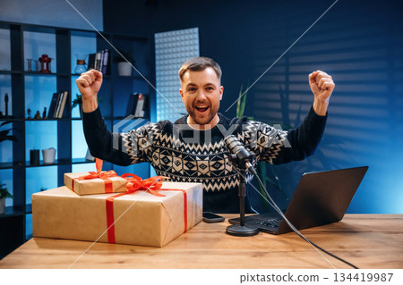 Christmas present, gift box. Man with microphone in the studio, conception of podcast 134419987