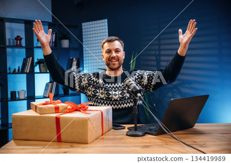 Present, new year gift box. Man with microphone in the studio, conception of podcast Present, new year gift box. Man with microphone in the studio, conception of podcast 134419989