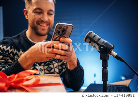 Present, new year gift box. Man with microphone in the studio, conception of podcast Present, new year gift box. Man with microphone in the studio, conception of podcast 134419991