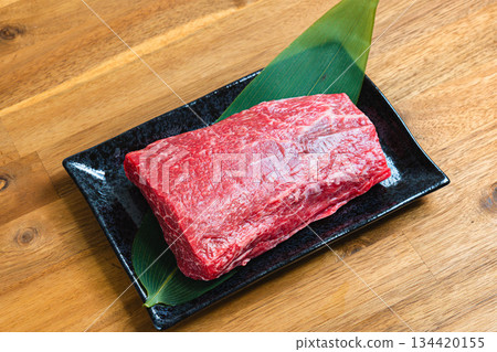 Beef shoulder block Raw meat ingredients photo Black dish and wood grain table Beef shoulder block Raw meat ingredients photo Black dish and wood grain table 134420155