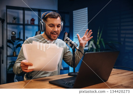 By the laptop. Man with microphone in the studio, conception of podcast 134420273