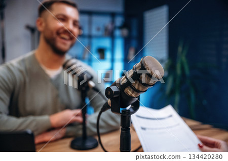 Sitting and smiling. Man with microphone in the studio, conception of podcast Sitting and smiling. Man with microphone in the studio, conception of podcast 134420280