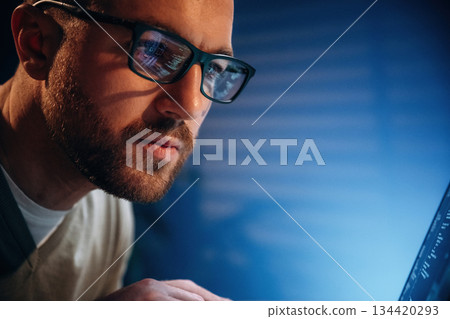 Focused on job. Male programmer is working indoors by a laptop 134420293