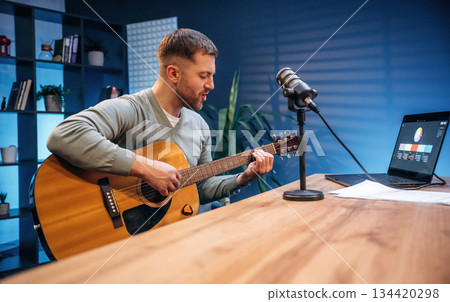 Songwriter with acoustic guitar. Man with microphone in the studio, conception of podcast Songwriter with acoustic guitar. Man with microphone in the studio, conception of podcast 134420298