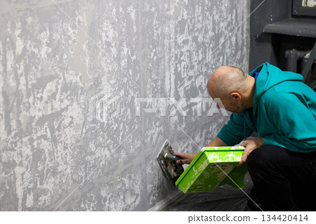 Close-up shot capturing a construction worker applying decorative plaster to a wall with a trowel Close-up shot capturing a construction worker applying decorative plaster to a wall with a trowel 134420414