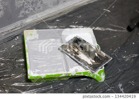 Close up, home renovation concept showing a paint tray filled with gray paint and a roller 134420419
