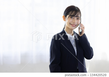 A young woman in a suit talking on a smartphone A young woman in a suit talking on a smartphone 134420520