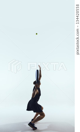 Padel player jumps upward hitting ball at peak height 134420558