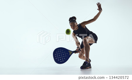 Female padel player controlling ball close to racket in studio. 134420572