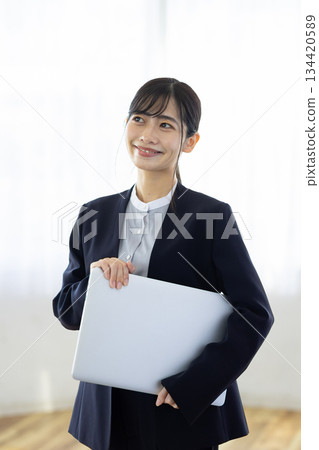 Smiling young businesswoman holding a laptop 134420589