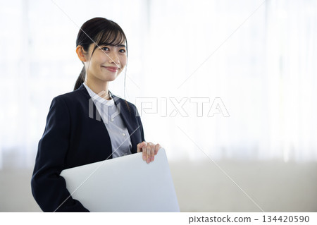 微笑的年輕女商人手持筆記型電腦 134420590