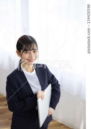 Smiling young businesswoman holding a laptop Smiling young businesswoman holding a laptop 134420596