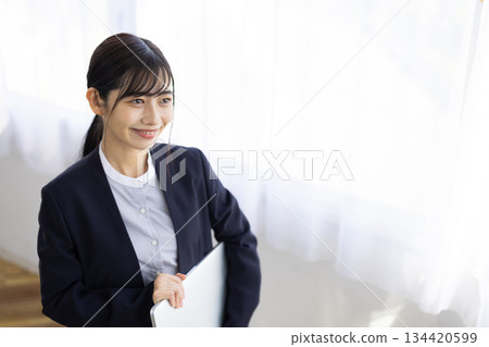 Smiling young businesswoman holding a laptop Smiling young businesswoman holding a laptop 134420599