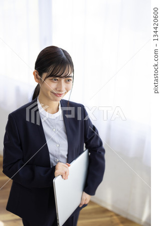 Smiling young businesswoman holding a laptop 134420600