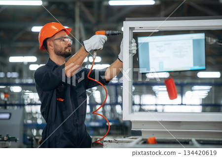 Maintaining the window, using screwdriver. Man is working in the modern factory Maintaining the window, using screwdriver. Man is working in the modern factory 134420619