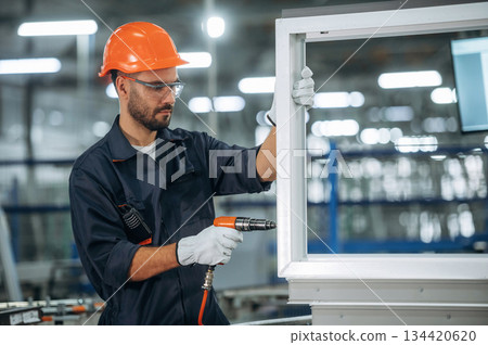 Maintaining the window, using screwdriver. Man is working in the modern factory 134420620