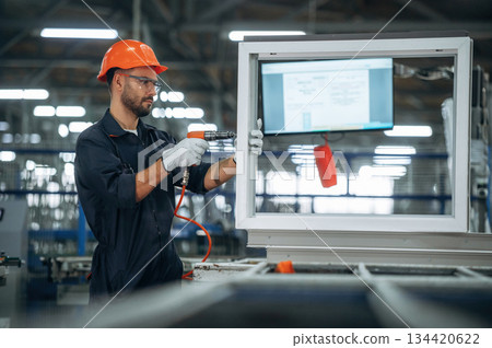 Maintaining the window, using screwdriver. Man is working in the modern factory 134420622