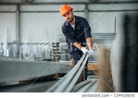 Bunch of metal planks in hands, front view. Man is working in the modern factory Bunch of metal planks in hands, front view. Man is working in the modern factory 134420650