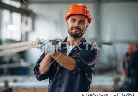 Holding metal pieces, planks. Man is working in the modern factory Holding metal pieces, planks. Man is working in the modern factory 134420661