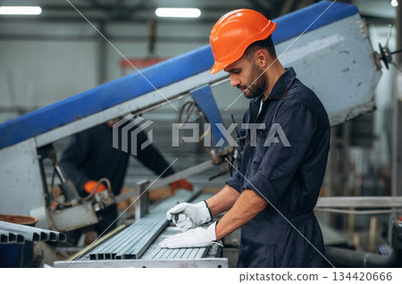 By the machine, operator is taking notes. Man is working in the modern factory By the machine, operator is taking notes. Man is working in the modern factory 134420666