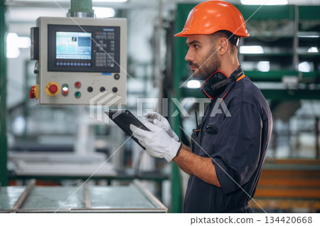 Operating the machine. Man is working in the modern factory Operating the machine. Man is working in the modern factory 134420668