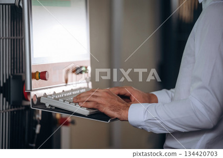 Typing on the keyboard. Close up view of man that is working in the modern factory Typing on the keyboard. Close up view of man that is working in the modern factory 134420703